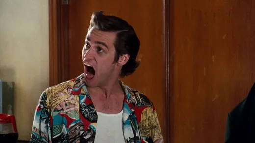 Jim Carrey as Ace Ventura, in a Hawaiian shirt with a quiff, making a face