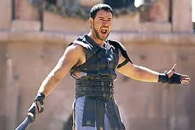 Maximus in gladiator armour, arms spread wide, shouting at a crowd