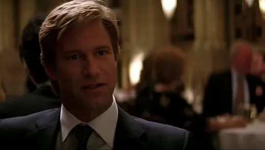Harvey Dent in a suit at a restaurant table, speaking seriously