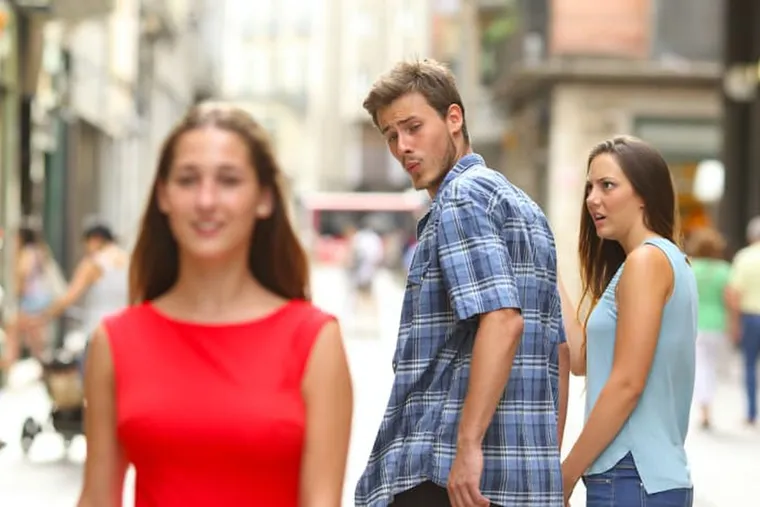 A man on a street turning to look at a woman in red while his girlfriend stares at him, outraged