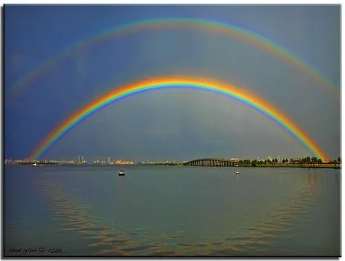 A double rainbow arching over a green landscape