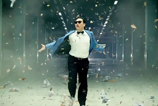 PSY in a suit and sunglasses doing the horse-riding dance