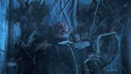 Hodor bracing a wooden door shut in a dark cave entrance