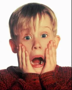 A young boy screaming with both hands pressed to his cheeks