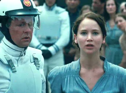 Katniss Everdeen stepping forward in a crowd, arm raised