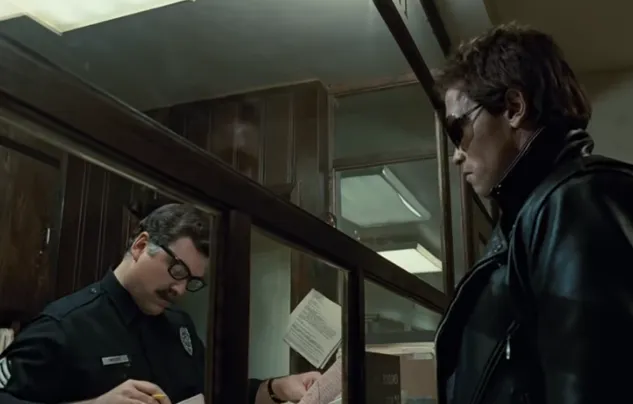 The Terminator in sunglasses and a leather jacket at a police station front desk