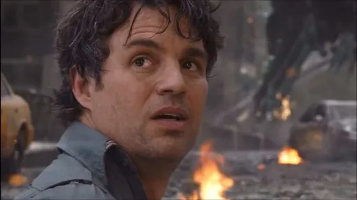 Bruce Banner turning his head with a calm, slightly ominous smile, in a city street