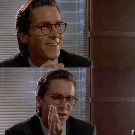 Patrick Bateman in a suit and slicked-back hair, holding up and studying a business card