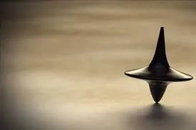A small metal spinning top spinning on a wooden table