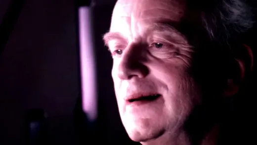 Chancellor Palpatine in a dim opera box, speaking with a knowing look