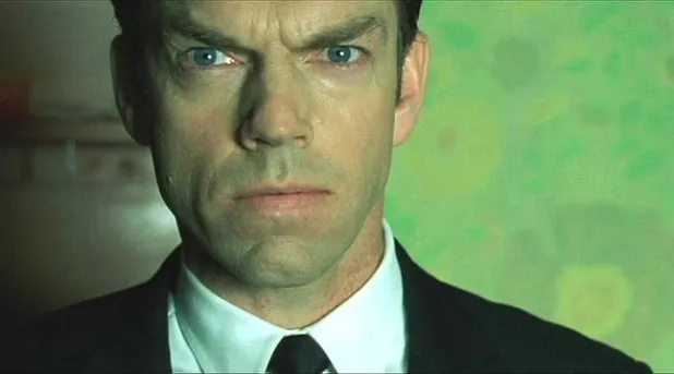Agent Smith in dark sunglasses and a suit, against a green background