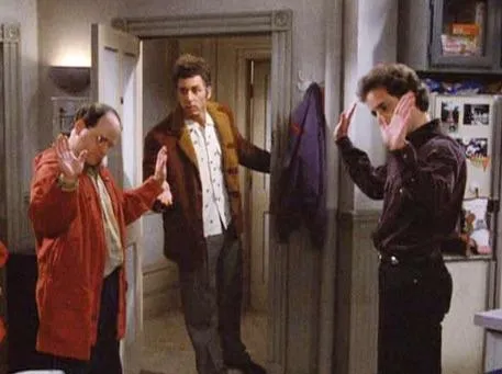 Jerry Seinfeld and George Costanza standing together in an apartment