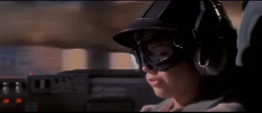 Young Anakin Skywalker in a podracing helmet and goggles, grinning in his cockpit