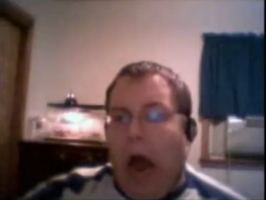 A young man in headphones lip-syncing enthusiastically in front of a webcam