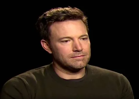 Ben Affleck in a dark shirt looking downcast and lost in thought