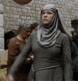 A stern nun in grey robes ringing a hand bell