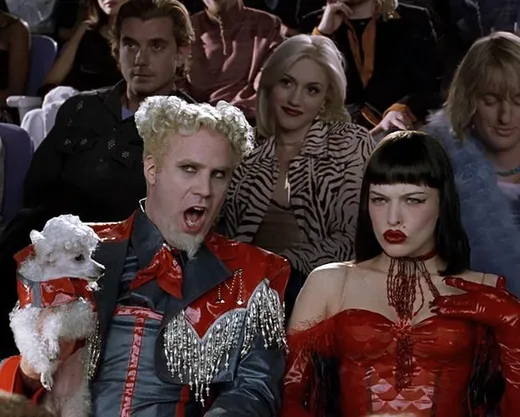 Will Ferrell as Mugatu with wild white hair, holding a small dog
