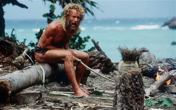 Tom Hanks as a bearded castaway on a rocky shore with a volleyball